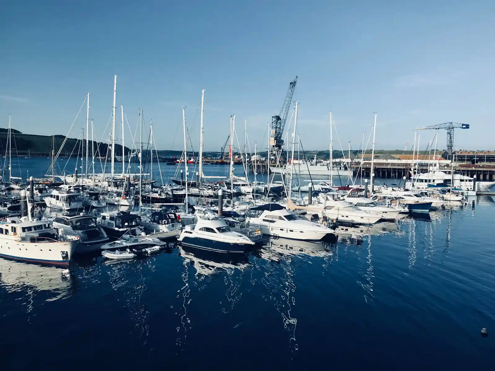 Boats moored at Falmouth with the dockyard cranes behind